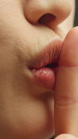 Close up female plump lips showing hush sign unknown woman holding index finger near mouth Asian Korean girl showing silence secrets quiet gesture deny reject stop talking private conspiracy concept
