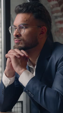 Pensive doubtful Hindu business man serious businessman thinking with laptop Indian millennial professional guy male pondering computer task at table brainstorm decide searching inspiration in office