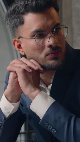 Pensive doubtful Hindu business man serious businessman thinking with laptop Indian millennial professional guy male pondering computer task at table brainstorm decide searching inspiration in office