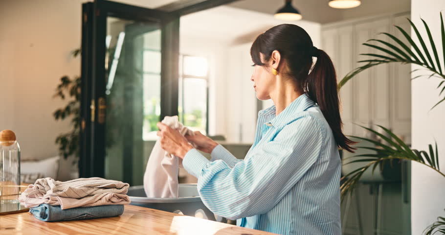 Laundry, fragrance or mature woman in home with clothing, housekeeping or scent in spring cleaning. Happy, comfort or person in living room with material, domestic chores or smell of fabric softener.