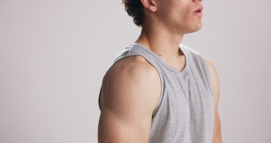 Fitness, athlete and shoulder stretching in studio for muscle relief, joint mobility and start workout. Mockup space, man and neck release exercise on white background with warm up and flexibility
