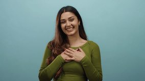 Woman smiling in green top against blue background gesturing happiness in a relaxed isolated setting showcasing joyful hispanic expression and positive vibes - Powered by Shutterstock - Get 15% off with code: PIKWIZARD15