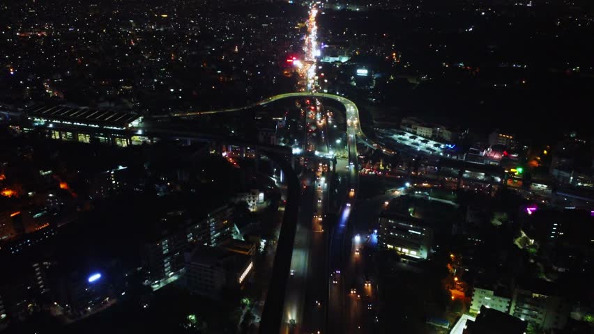 Drone shot of Night time traffic at Silk Board Junction in Bangalore, Karnataka, India.  Chaotic urban congestion with glowing vehicle lights and city movement	