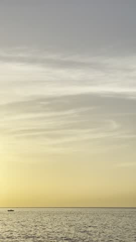 Small boat sailing under a golden sunset over the Atlantic Ocean in Gran Canaria. Warm light, calm sea, and soft clouds create a peaceful and cinematic seascape.