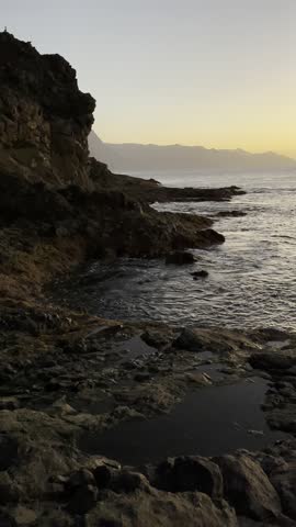 Golden sunset over the rocky coastline of Gran Canaria, with gentle ocean waves and warm light reflecting on volcanic pools. A calm and inspiring seascape in Sardina.