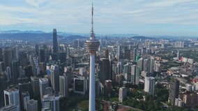 KL Tower dominates Kuala Lumpur, Malaysia as the drone glides above a dense skyline and green parkland in bright daylight. Morning clarity highlights business energy, architecture and tourism appeal - Powered by Shutterstock - Get 15% off with code: PIKWIZARD15