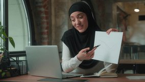 Muslim islamic business woman presenting good result marketing financial growth talking video call with laptop in office girl in hijab smiling female businesswoman saleswoman speak pointing on paper - Powered by Shutterstock - Get 15% off with code: PIKWIZARD15