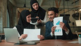 Muslim business team presenting data stats on video call laptop meeting in office three partners Arabian businesswomen in hijab Indian businessman showing documents growth financial graphs negotiation - Powered by Shutterstock - Get 15% off with code: PIKWIZARD15