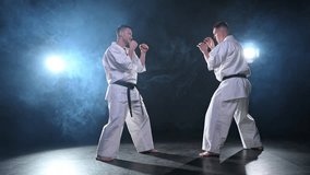 Martial arts masters on dark background. Strong man fighters in white kimono for karate martial arts fighting training in black gym. Karate fighters training punches kicks practicing fight sparring - Powered by Shutterstock - Get 15% off with code: PIKWIZARD15