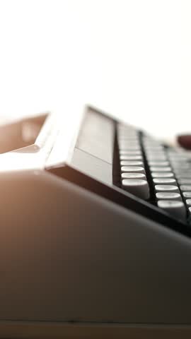 Writer's hands press keys on a typewriter, conveying a sense of creativity and passion for storytelling in a bright environment.