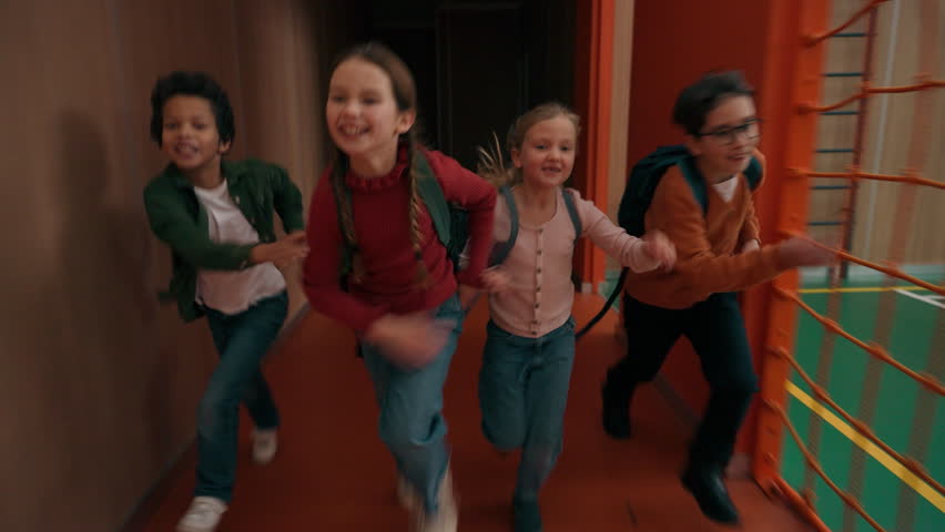 Happy smiling joyful multiracial four classmates kids children quickly running to classroom in school corridor multiethnic girls boys late class studying education run rush hurry to lesson having fun