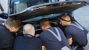 Technicians group conduct diagnostics of car engine with smartphone at service station rear view. Mechanics checks damage of vehicle in repair shop - Powered by Shutterstock - Get 15% off with code: PIKWIZARD15