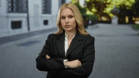 Woman outdoors on city street, confidently posing in black blazer, blonde hair flowing, conveying urban professional vibe on a bright day. - Powered by Shutterstock - Get 15% off with code: PIKWIZARD15