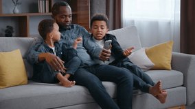 African American happy family using mobile phone father with little sons boys at home having fun browsing social media dad with two kids children talking order food delivery cellphone gadget addict - Powered by Shutterstock - Get 15% off with code: PIKWIZARD15