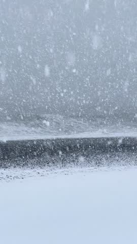 Heavy snowstorm over rough sea with high waves winter blizzard extreme coastal weather. 