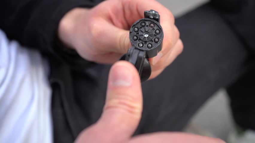 A man is loading caps into a cap gun and getting ready to shoot.