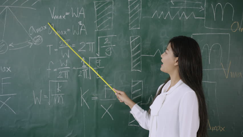 Back to school in summer. Happy Asian young female math teacher standing holding a pointer and teaching a mathematics lesson on chalkboard in front of the classroom, Concept of learning and education. - Powered by Shutterstock - Get 15% off with code: PIKWIZARD15