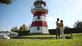 Romantic couple embracing and kissing near a red and white lighthouse on a sunny day, symbolizing love, travel, and peaceful moments by the coast. - Powered by Shutterstock - Get 15% off with code: PIKWIZARD15
