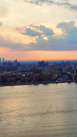Scenic sunset over New York skyline with ferry on the river and dramatic clouds. Aerial view. Vertical video.