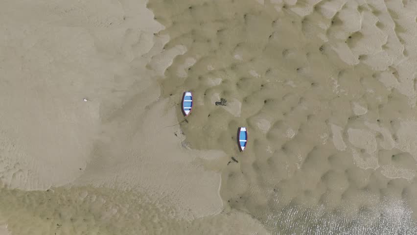 Minimalist boat aerial. Two colorful boats moored on a textured sand beach at low tide, perfect for abstract art prints.