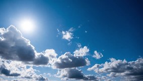Fast motion time-lapse of puffy white and grey clouds floating across deep blue sky, passing the bright shining sun, revealing patches of clear sky and casting dynamic shadows on a sunny day. - Powered by Shutterstock - Get 15% off with code: PIKWIZARD15