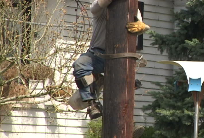 Person from power company doing repair work on power line, climbs down.