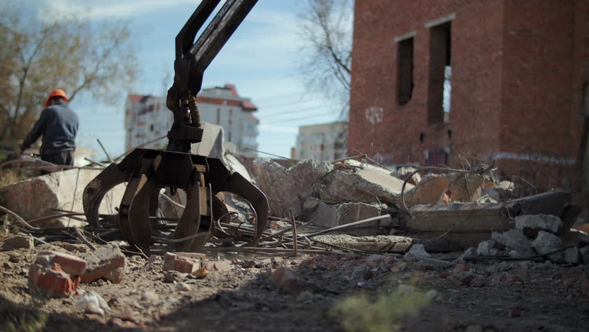 Excavator claw clearing debris after building demolition