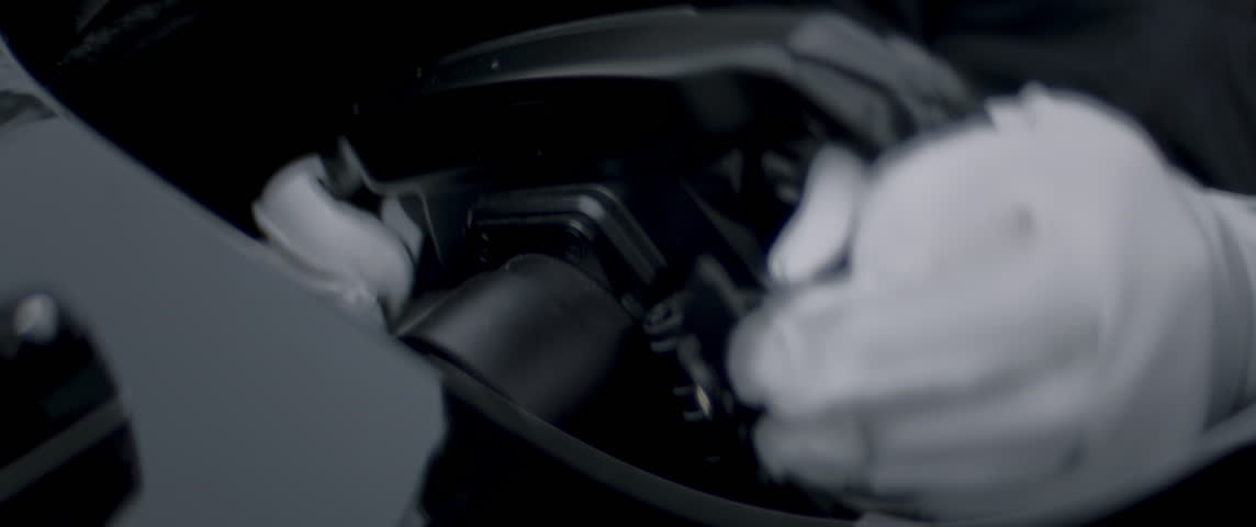 Close-up of a race car driver in white gloves driving fast on a racing track, evening race