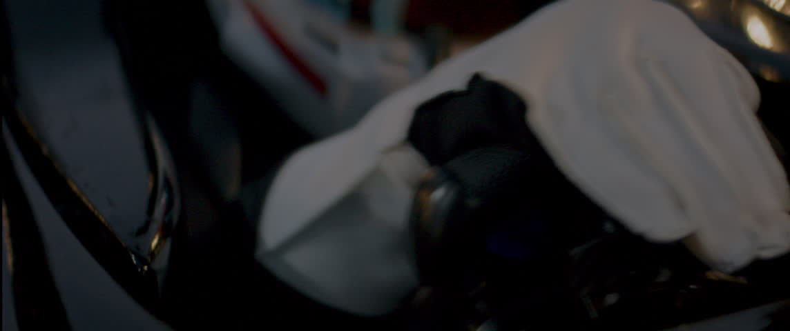 Close-up of a race car driver in a white helmet with red details, driving fast on a racing track, evening race