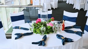 Elegant round dining table set on cruise ship. Beautifully decorated round table with white cloth, blue napkins, and floral centerpiece in cruise dining hall. - Powered by Shutterstock - Get 15% off with code: PIKWIZARD15