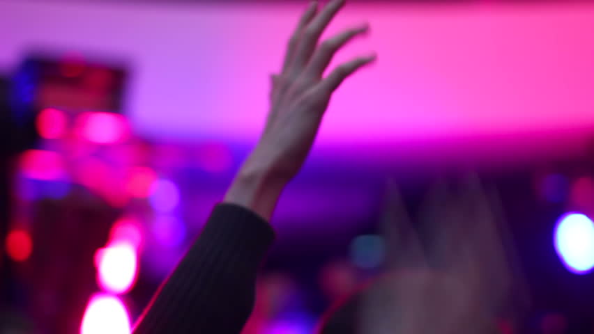 Waving hands of clubbing people in air in night club during party