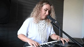 Caucasian woman singing into microphone and playing synthesizer and recording herself on laptop.  - Powered by Shutterstock - Get 15% off with code: PIKWIZARD15