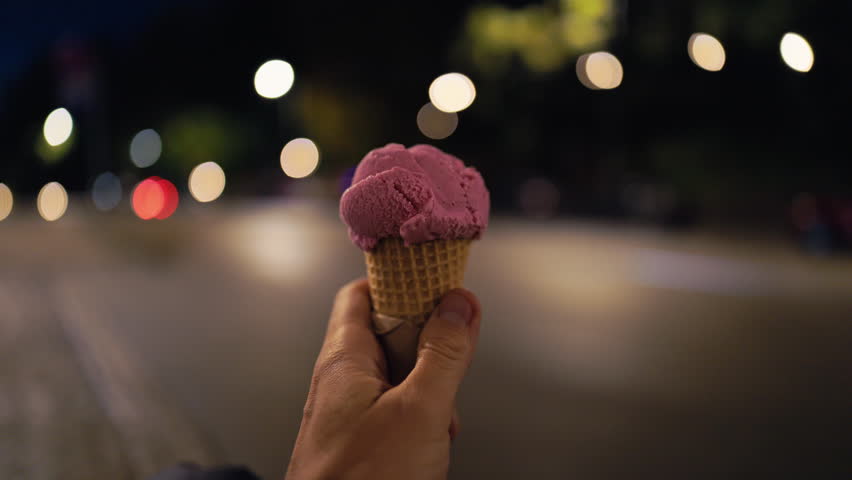 Hand with ice cream, Pink ice cream in hand, Holding pink ice cream near moving car lights