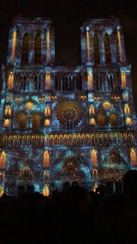 Notre Dame Cathedral in Paris illuminated during a vibrant light show at night, highlighting Gothic architecture, dramatic colors, and the iconic French landmark.
