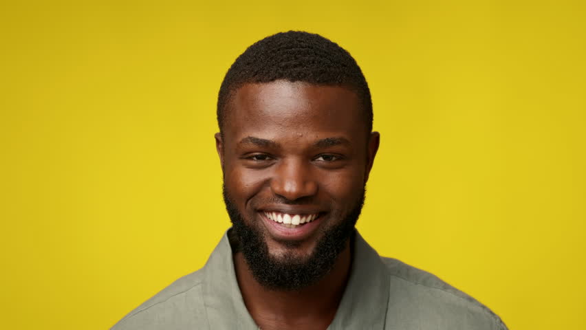 Smiling African American man in casual attire against bright yellow background