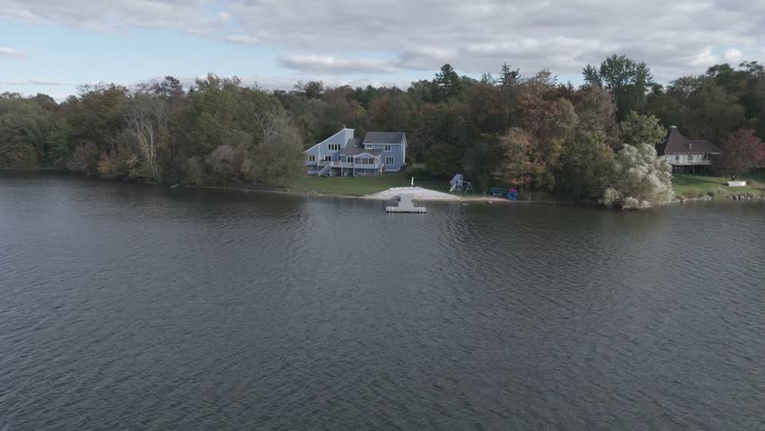 Aerial view of a peaceful Connecticut lake with wooden decks and empty chairs, surrounded by lush greenery—perfect for relaxation and nature themes.