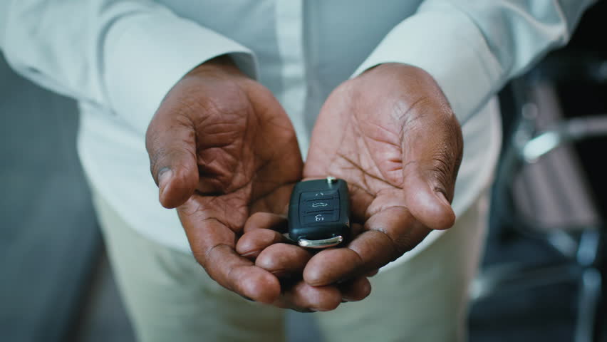 Mature African American businessman holding car keys in corporate office setting