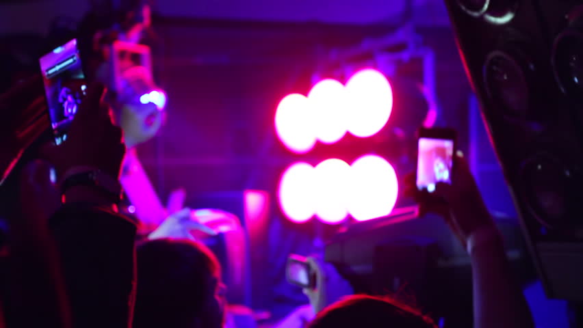 People in crowd shooting DJ using their phones in night club