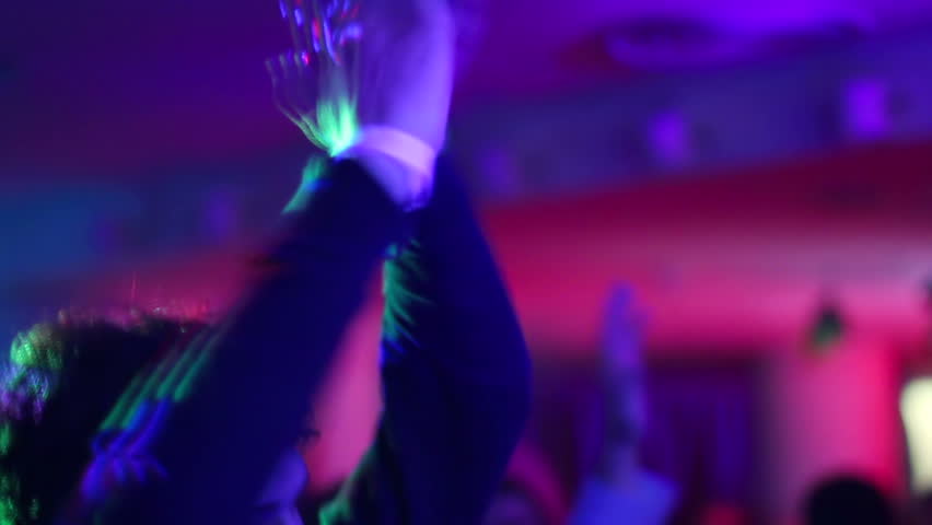 Clapping hands with wrist band (club bracelet) on dance floor in night club