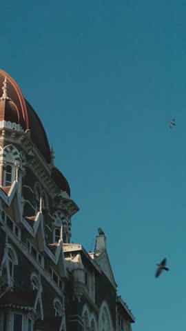Mumbai, India. Close-up View On Taj Mahal Palace Is Heritage, Five-star, Luxury Hotel In Colaba Area Of Mumbai Situated Next To Gateway Of India. Blue Clear Sky In Sunny Day With Fly Birds In Slow