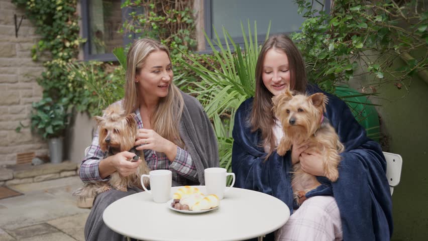 Enjoying morning coffee with small dogs in a cozy garden setting on a sunny day