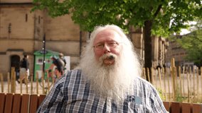 Bearded man enjoys sunny day at the park while relaxing on a bench near historic architecture - Powered by Shutterstock - Get 15% off with code: PIKWIZARD15