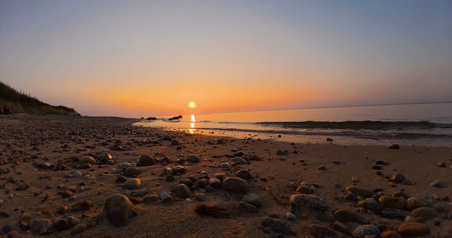 Timelapse sunset video on a sandy beach over the ocean.
