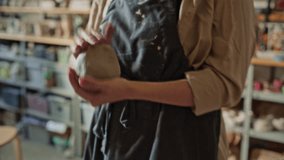 Young female artisan kneading clay ball with her hands in ceramics studio before throwing it on pottery wheel. Close-up shot - Powered by Shutterstock - Get 15% off with code: PIKWIZARD15