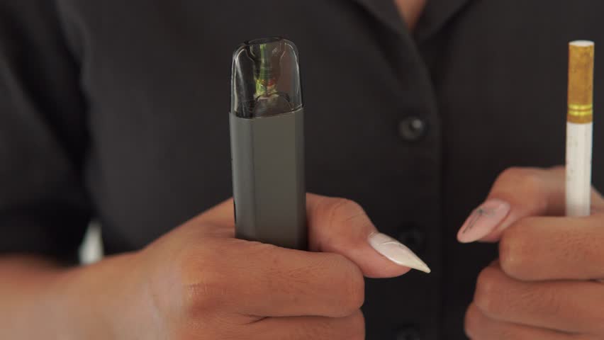 Close up of an Asian woman holding cigarette and a vape electric cigarette.