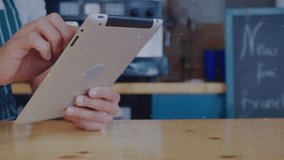 Barista tapping tablet at cafe counter and accessing live sales data with rotating circuit rings. Technology, digital, innovation, modern, hospitality, business, interface - Powered by Shutterstock - Get 15% off with code: PIKWIZARD15