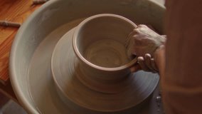 Hands of female artisan shaping clay into rounded bowl on spinning pottery wheel in ceramics studio. Close-up view - Powered by Shutterstock - Get 15% off with code: PIKWIZARD15