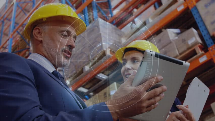Man and woman in safety helmets holding tablet analyzing warehouse data via pulsing digital overlay. Collaboration, technology, industrial, teamwork, analytics, productivity, corporate - Powered by Shutterstock - Get 15% off with code: PIKWIZARD15