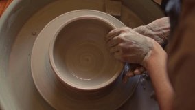 Hands of female ceramic artist crafting clay bowl on spinning pottery wheel in workshop. Directly above, close-up shot - Powered by Shutterstock - Get 15% off with code: PIKWIZARD15