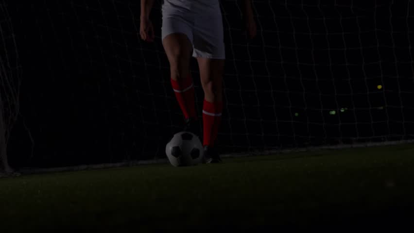Soccer player tapping ball to keep control while sports analytics overlay filling under floodlights. Athletic, performance, digital, technology, competition, nighttime, intensity